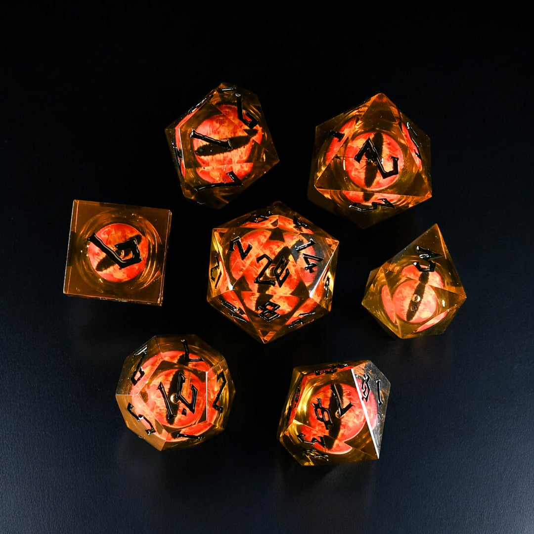 A set of resin liquid core dice with a flaming eye design, featuring yellow and black colors on a dark background.