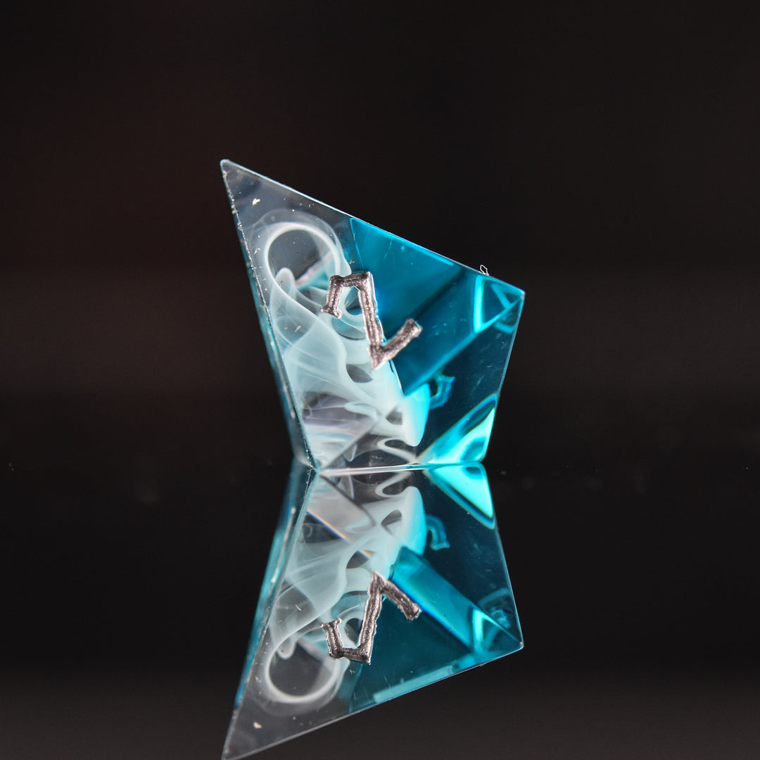 A collection of sharp-edged, blue and white resin dice with silver engraved numbers, reflecting on a black surface.