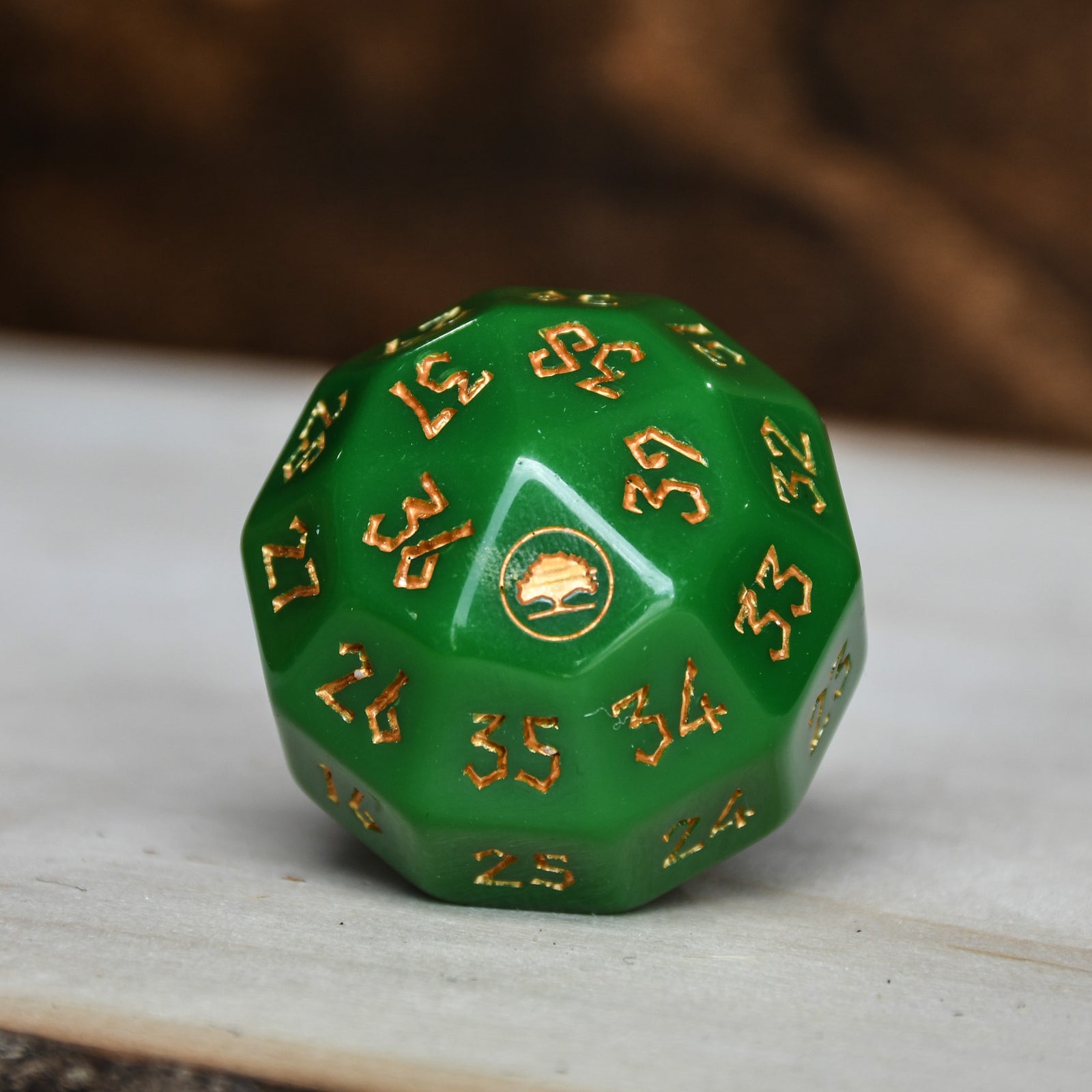 A green acrylic dice with engraved numbers and a symbol on one face, placed on a wooden surface.