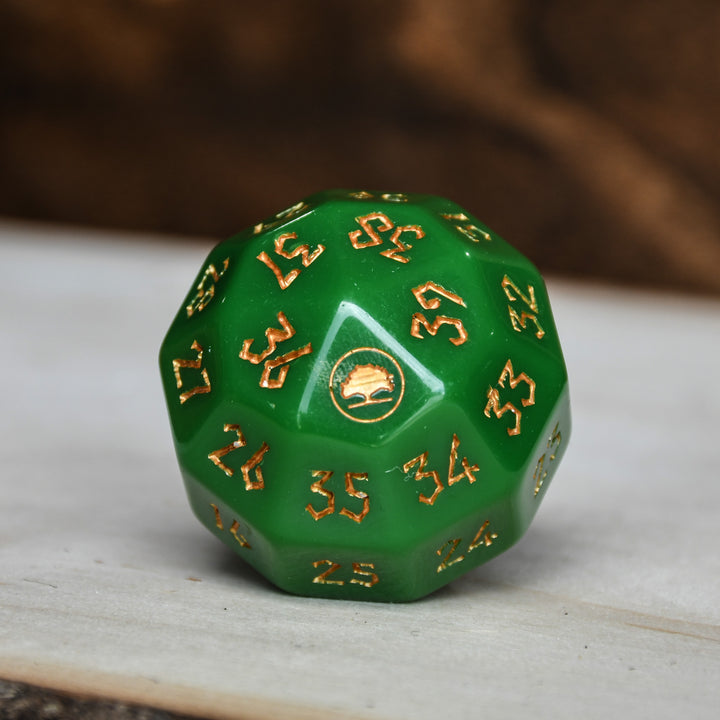 A green acrylic dice with engraved numbers and a symbol on one face, placed on a wooden surface.