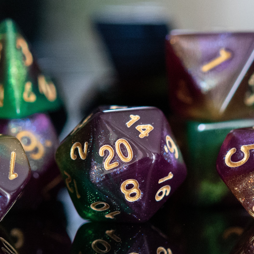 Close-up of polyhedral dice with gold numbers on a reflective surface.