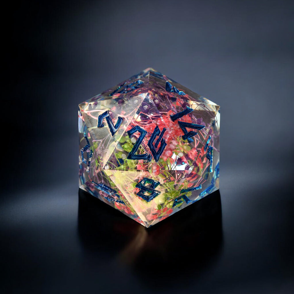 A hand-crafted blue and multicolor resin dice with hand-painted numbers, a 30mm D20, on a dark background.