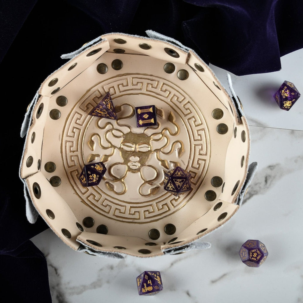 A set of purple amethyst stone dice with gold engraved designs in a dnd dice tray.