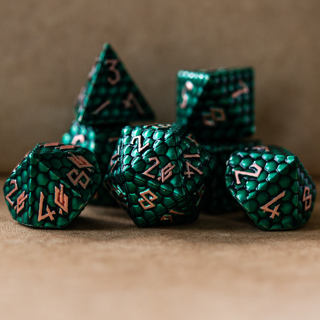 A set of green metal dice with embossed numbers, including various shapes such as a d4, d6, d8, d10, d12, and d20, displayed on a textured background.
