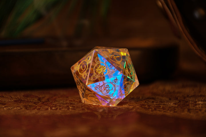 A multicolored prismatic glass d20 dice with Devanagari numerals, placed on a fabric with a peacock feather design, illuminated from below.