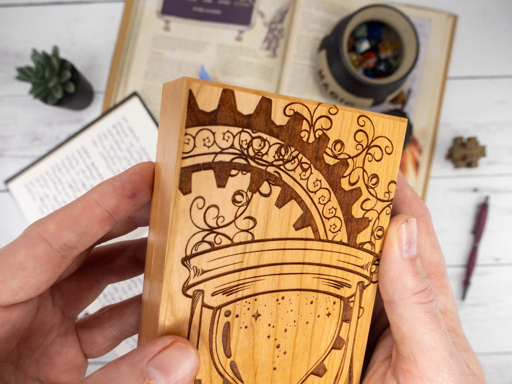 Wooden dice box with intricate carvings held by hands on a light wooden surface.