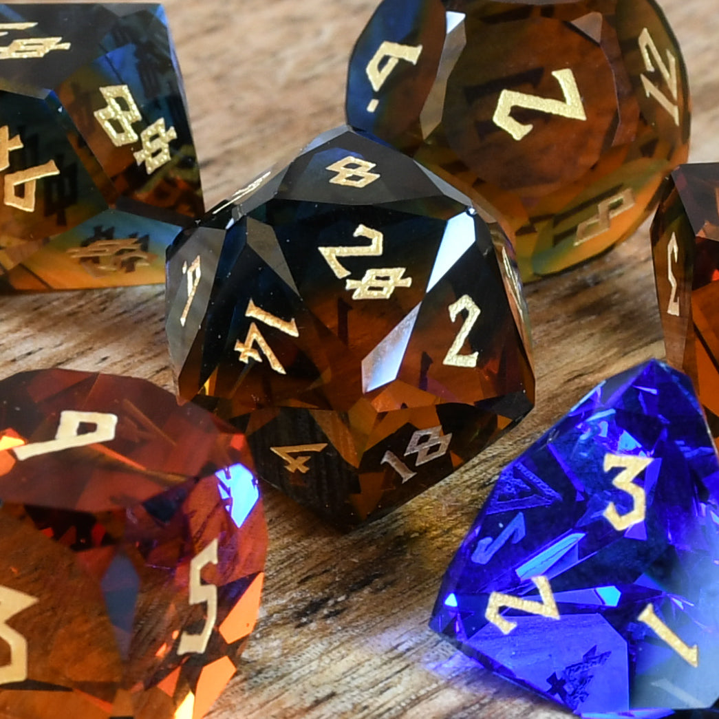 A set of multifaceted glass dice with engraved numbers, including various shapes such as a four-sided die (D4), six-sided die (D6), eight-sided die (D8), ten-sided die (D10), twelve-sided die (D12), and twenty-sided die (D20). The dice are placed on a wooden surface.