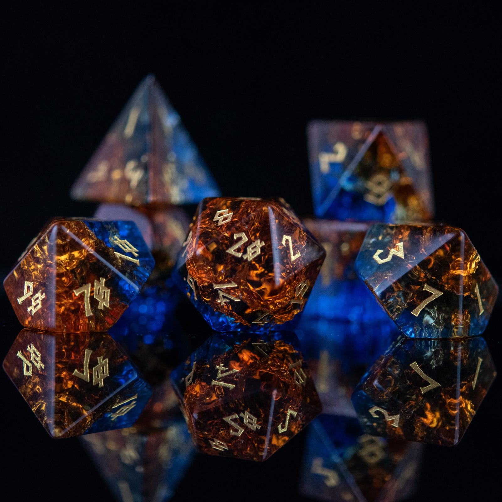 A set of hand-carved, shattered glass dice with engraved numbers, featuring a mix of blue and orange colors.