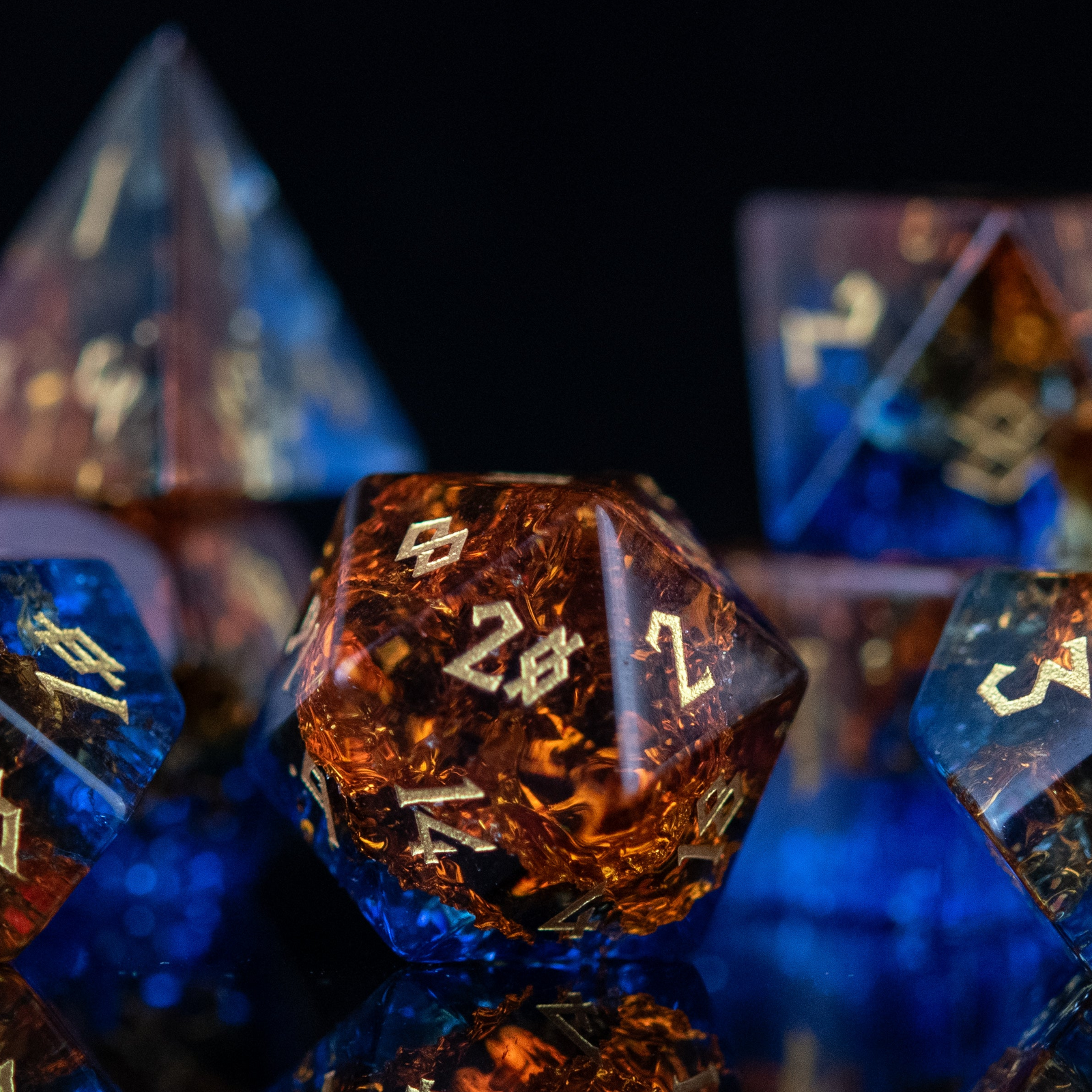 A set of hand-carved, shattered glass dice with engraved numbers, featuring a mix of blue and orange colors.