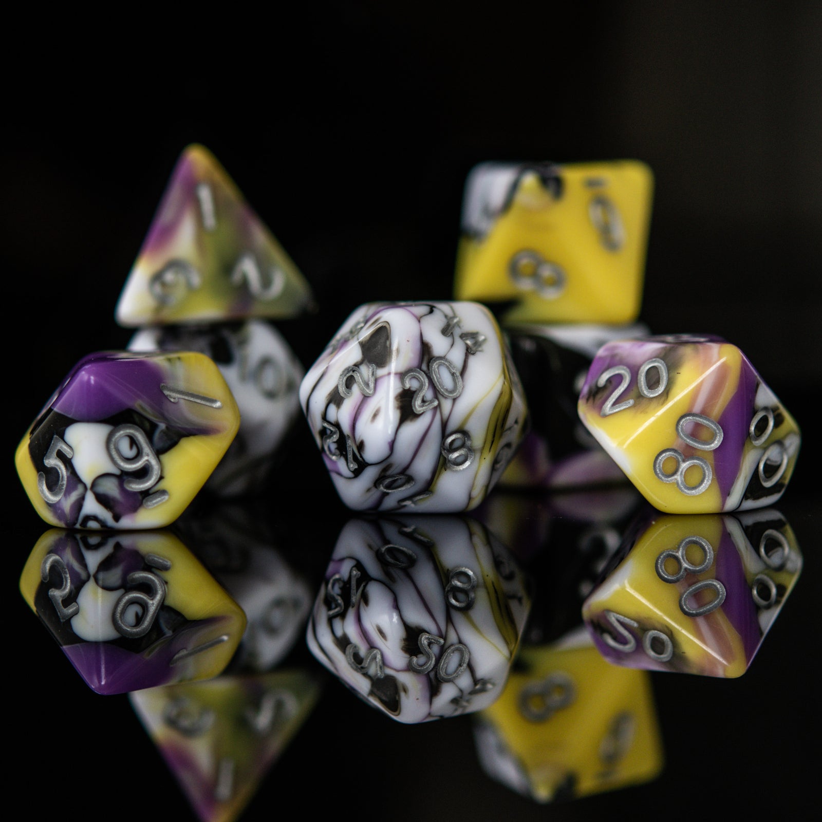 A set of acrylic dnd dice with black, white, yellow, and purple colors, featuring engraved silver numbers.