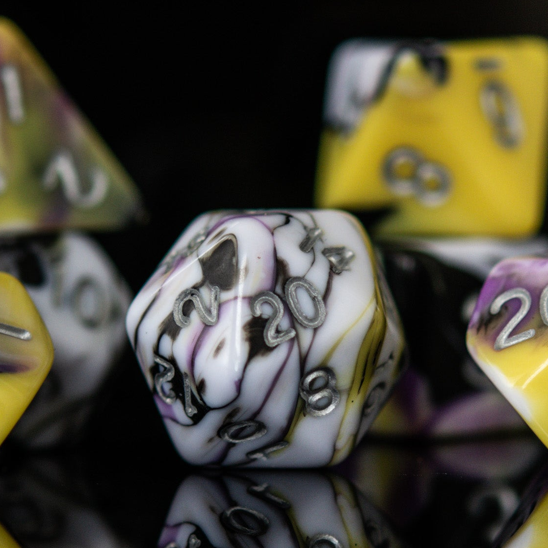 A set of acrylic dnd dice with black, white, yellow, and purple colors, featuring engraved silver numbers.