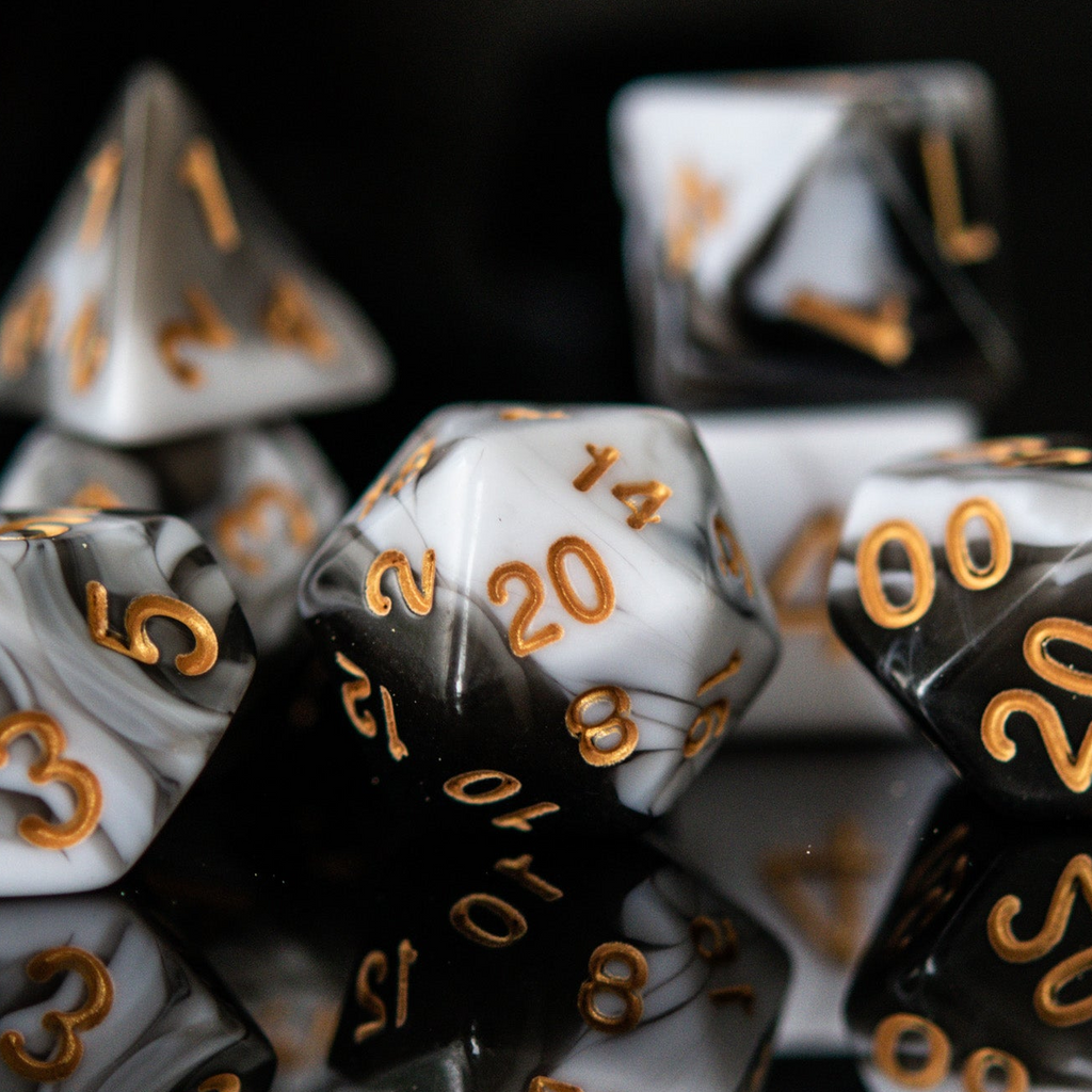 Close-up of a D20 polyhedral dice with black and white color scheme and gold numbers.