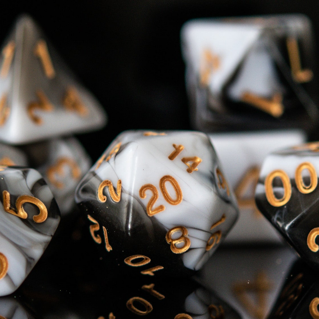A set of acrylic dnd dice featuring white and black colors with gold numbering.