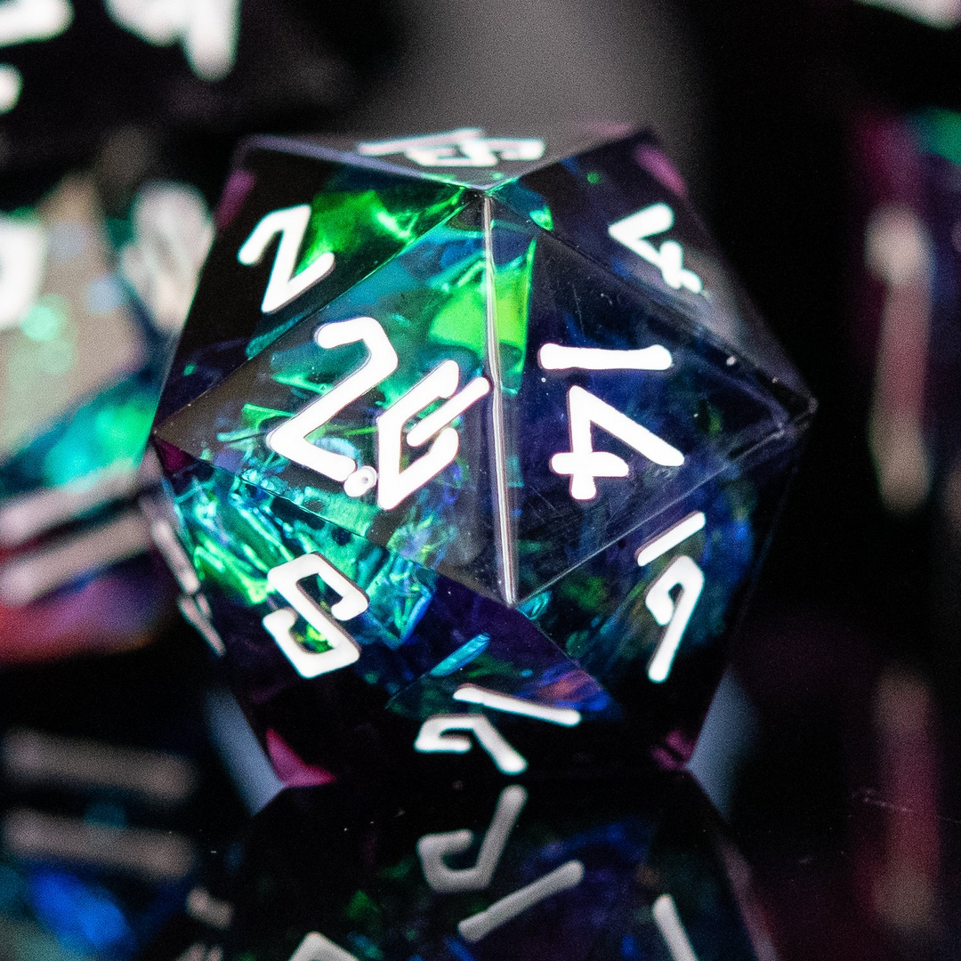 A collection of sharp-edged resin dice in black with hand-painted white numbers, featuring a metallic foil inside with hints of purple, green, and blue.