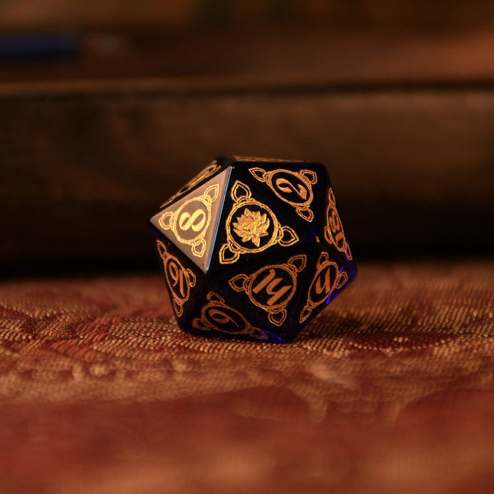 A set of hand-carved blue glass dice with golden designs inspired by Indian 