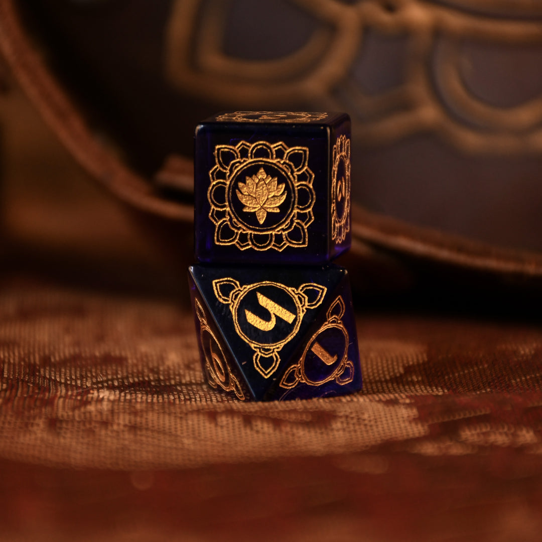 A set of hand-carved blue glass dice with golden designs inspired by Indian 