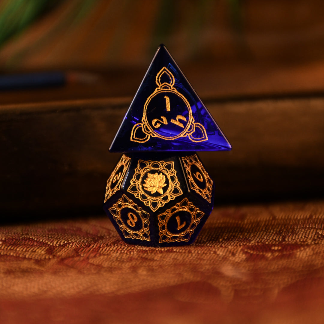 A set of hand-carved blue glass dice with golden designs inspired by Indian 