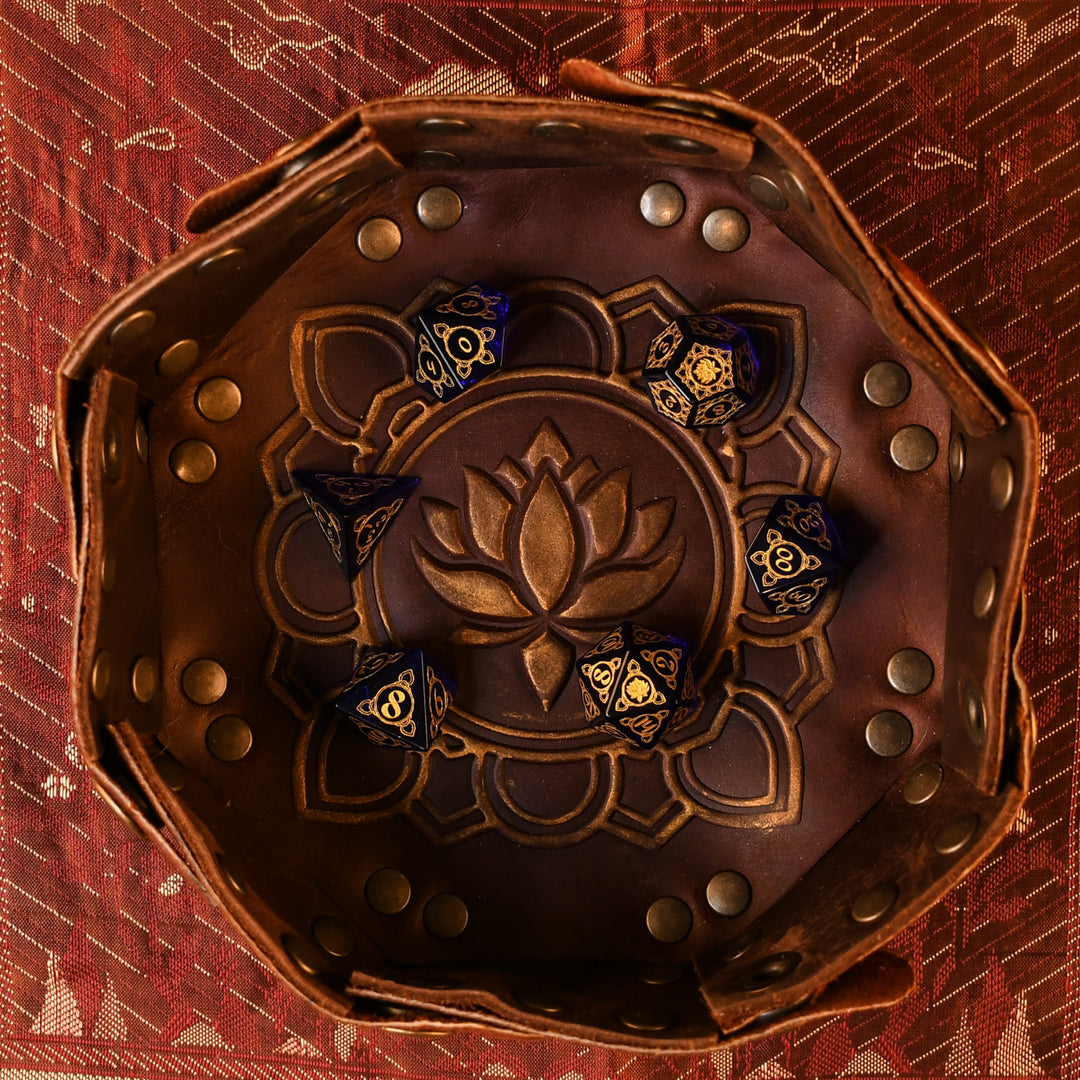 A set of hand-carved blue glass dice with golden designs inspired by India in a leather dnd dice tray