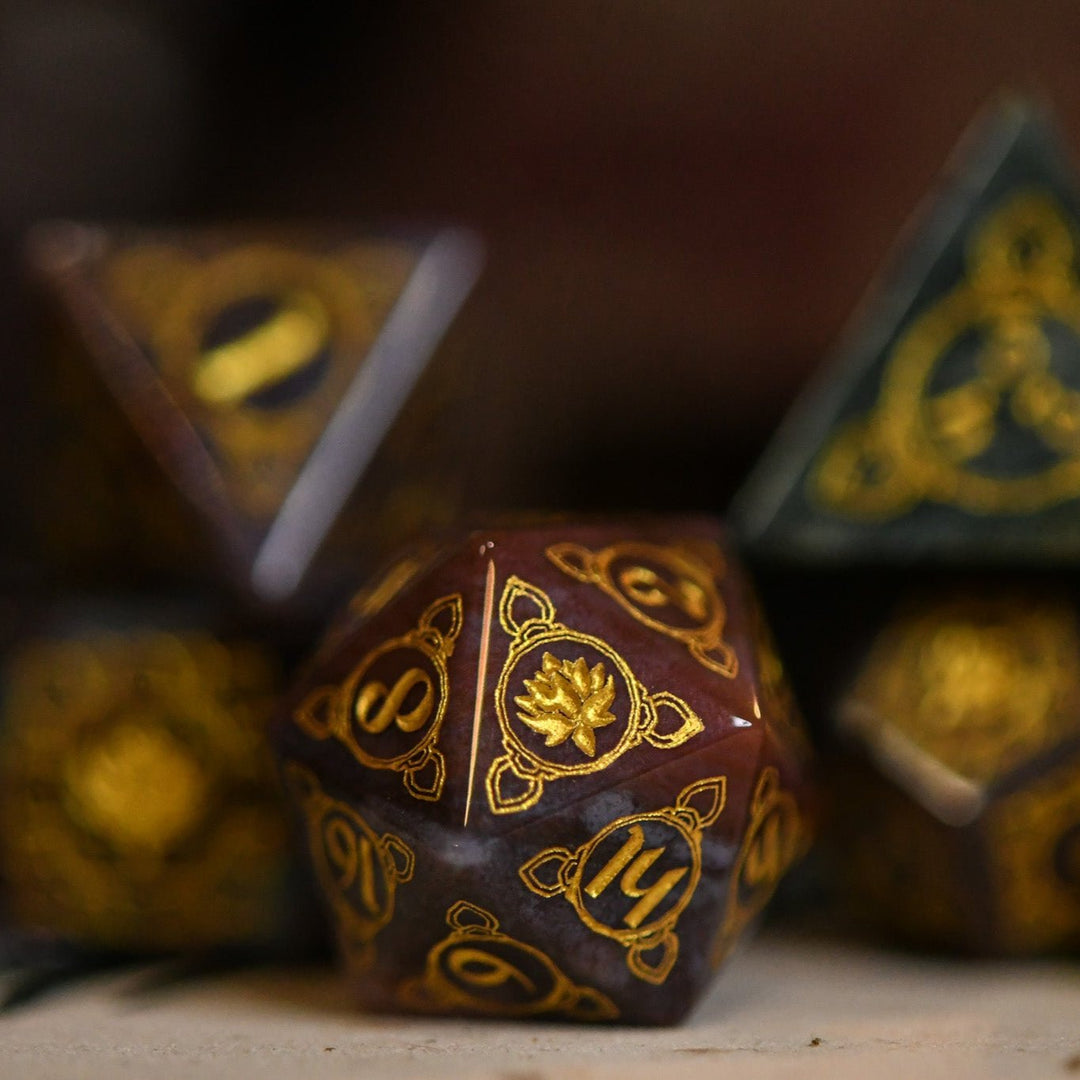 A set of hand-carved Indian Agate stone dnd dice with engraved patterns, displayed on a wooden surface.