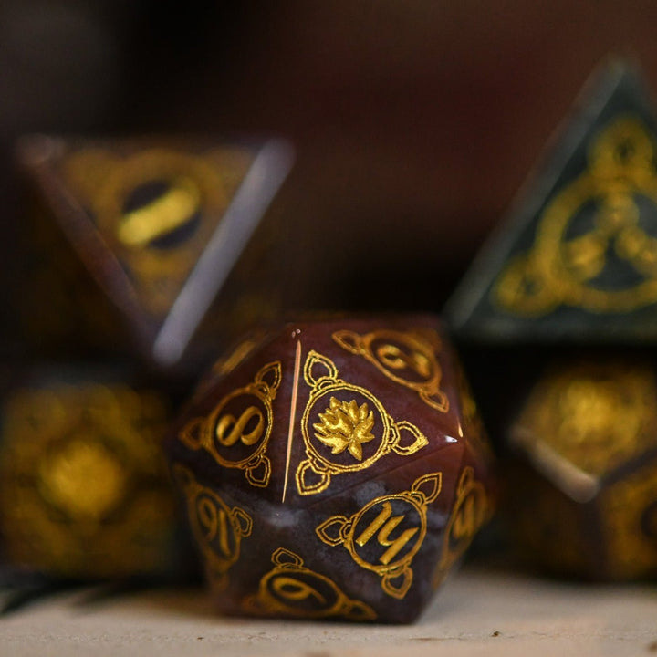 A set of hand-carved Indian Agate stone dnd dice with engraved patterns, displayed on a wooden surface.
