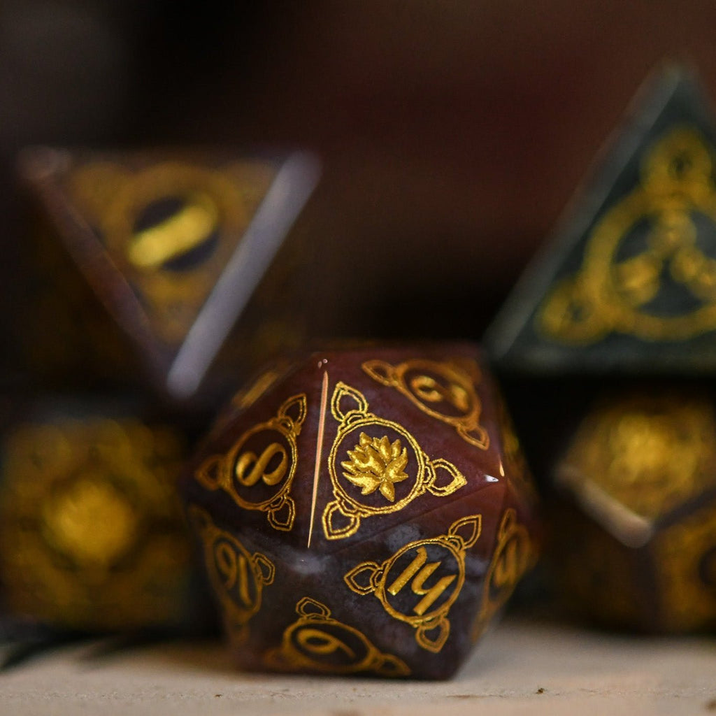 A set of hand-carved Indian Agate stone dnd dice with engraved patterns, displayed on a wooden surface.