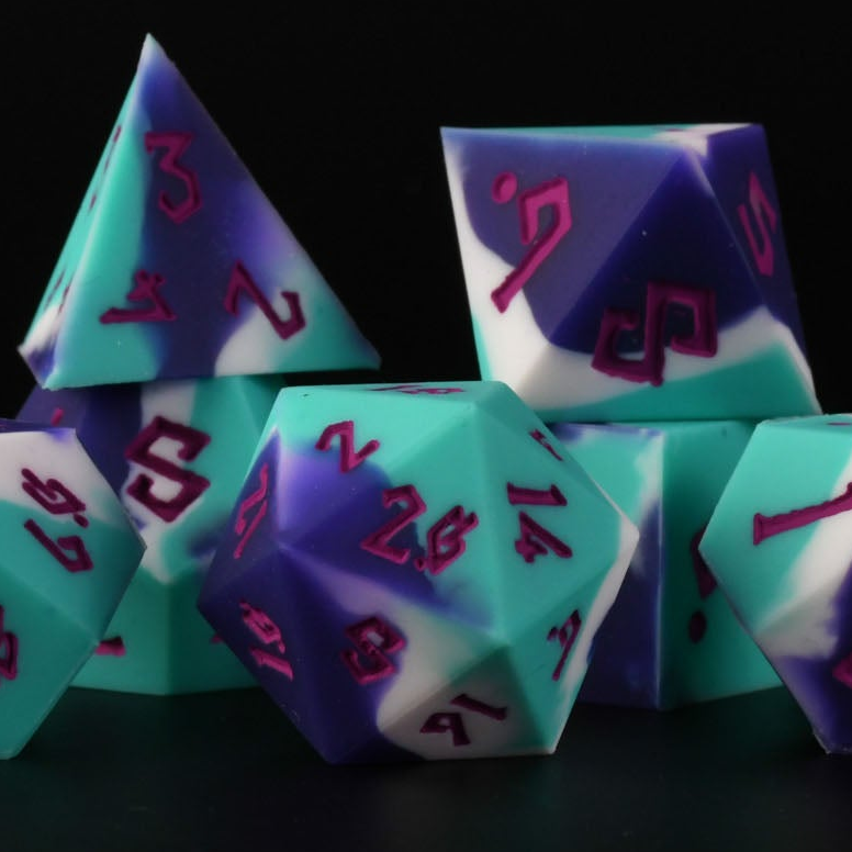 A set of silicone dice in green and purple colors with engraved numbers, including various shapes typical for role-playing games.