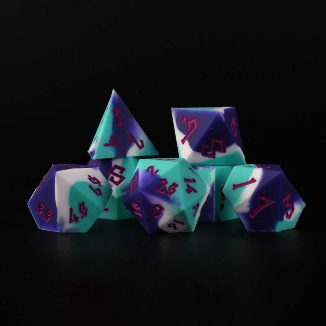 A set of silicone dice in green and purple colors with engraved numbers, including various shapes typical for role-playing games.