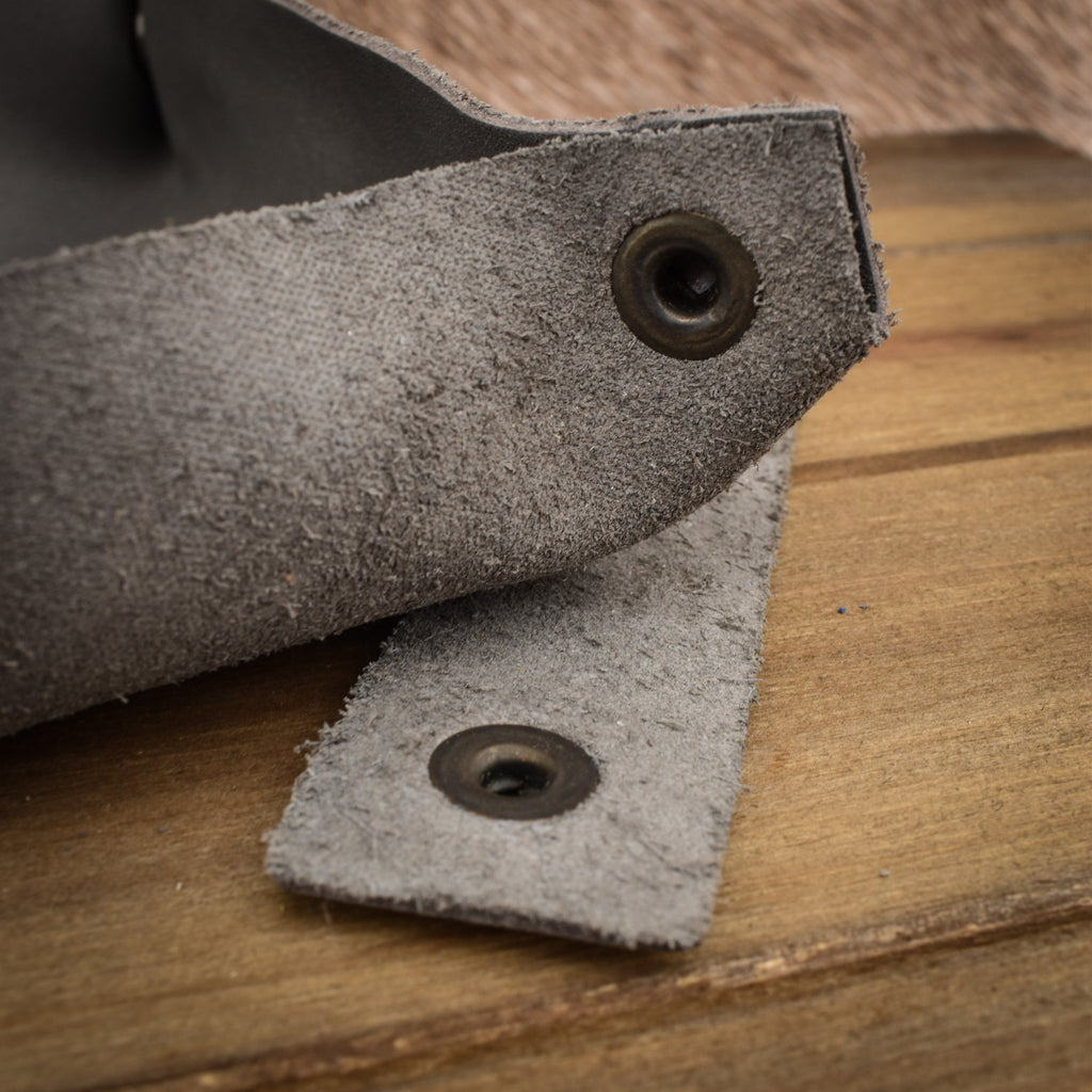 A grey leather collapsible dice tray on a wooden surface, with the tray unfolded next to its collapsed state.
