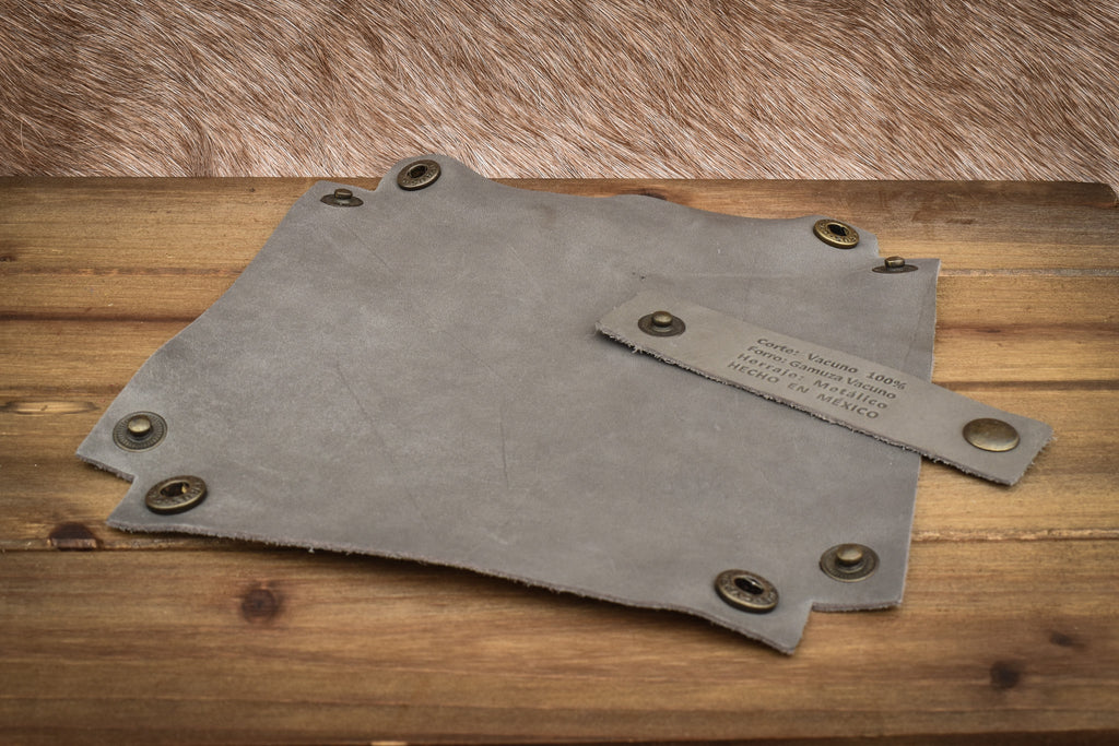 A grey leather collapsible dice tray on a wooden surface, with the tray unfolded next to its collapsed state.