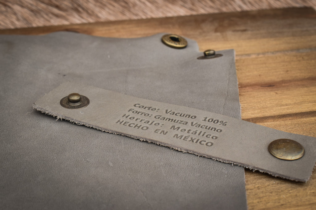 A grey leather collapsible dice tray on a wooden surface, with the tray unfolded next to its collapsed state.