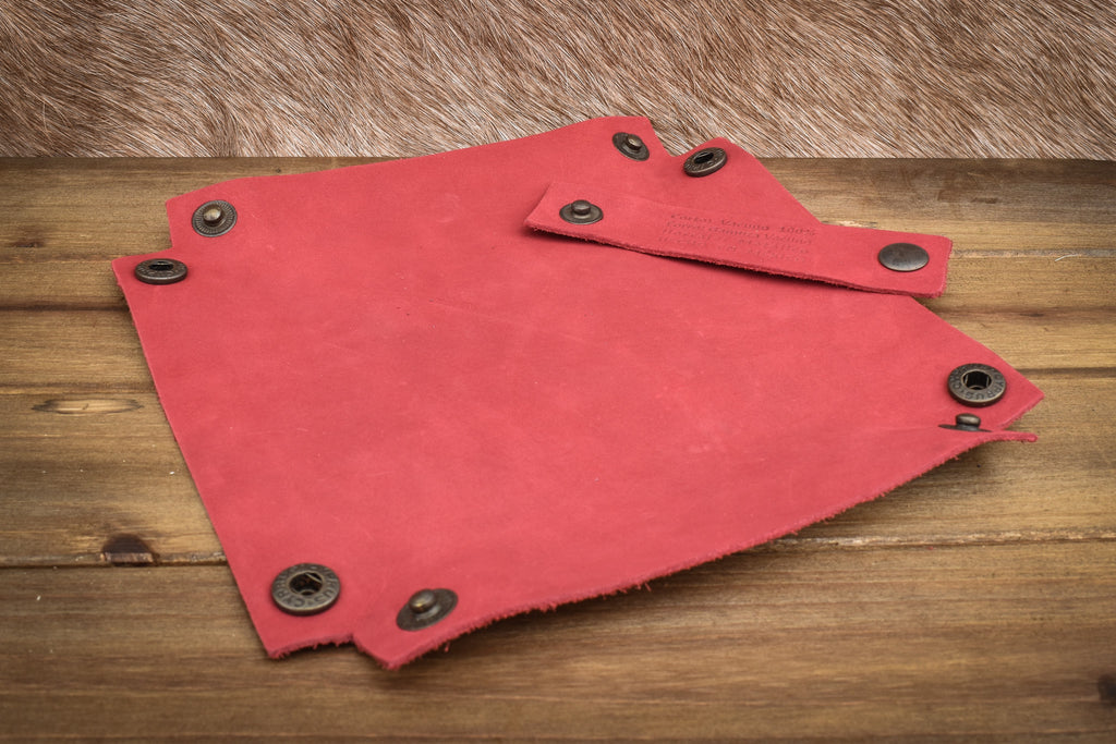 A red leather collapsible dice tray on a wooden surface, with the tray both folded and unfolded showing the compact and expanded states.