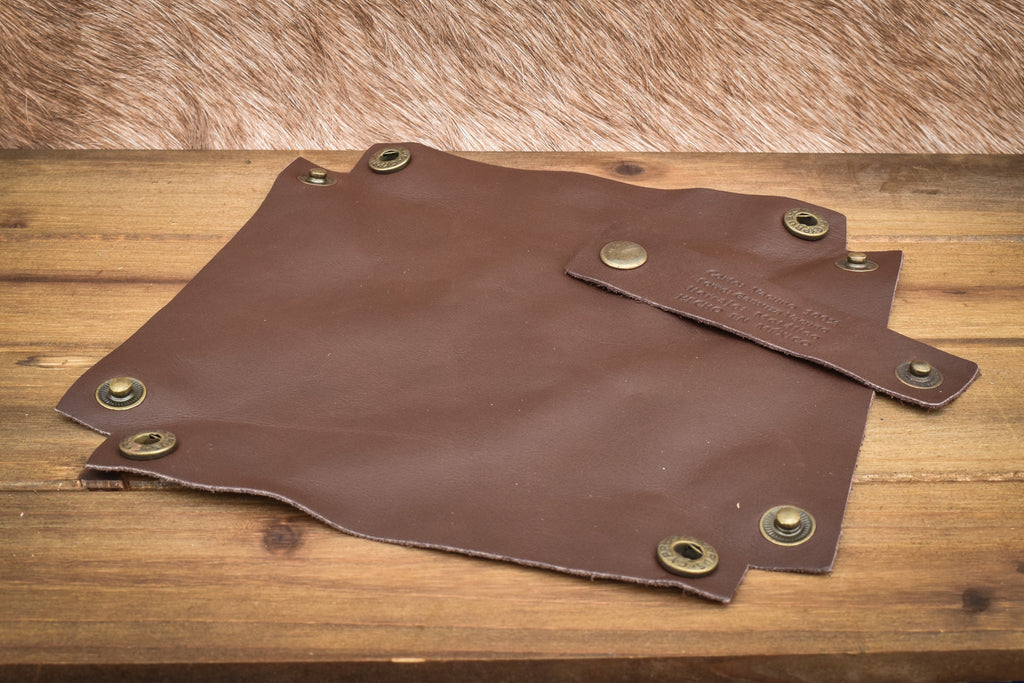 A semi-gloss brown leather collapsible dice tray displayed on a wooden surface.