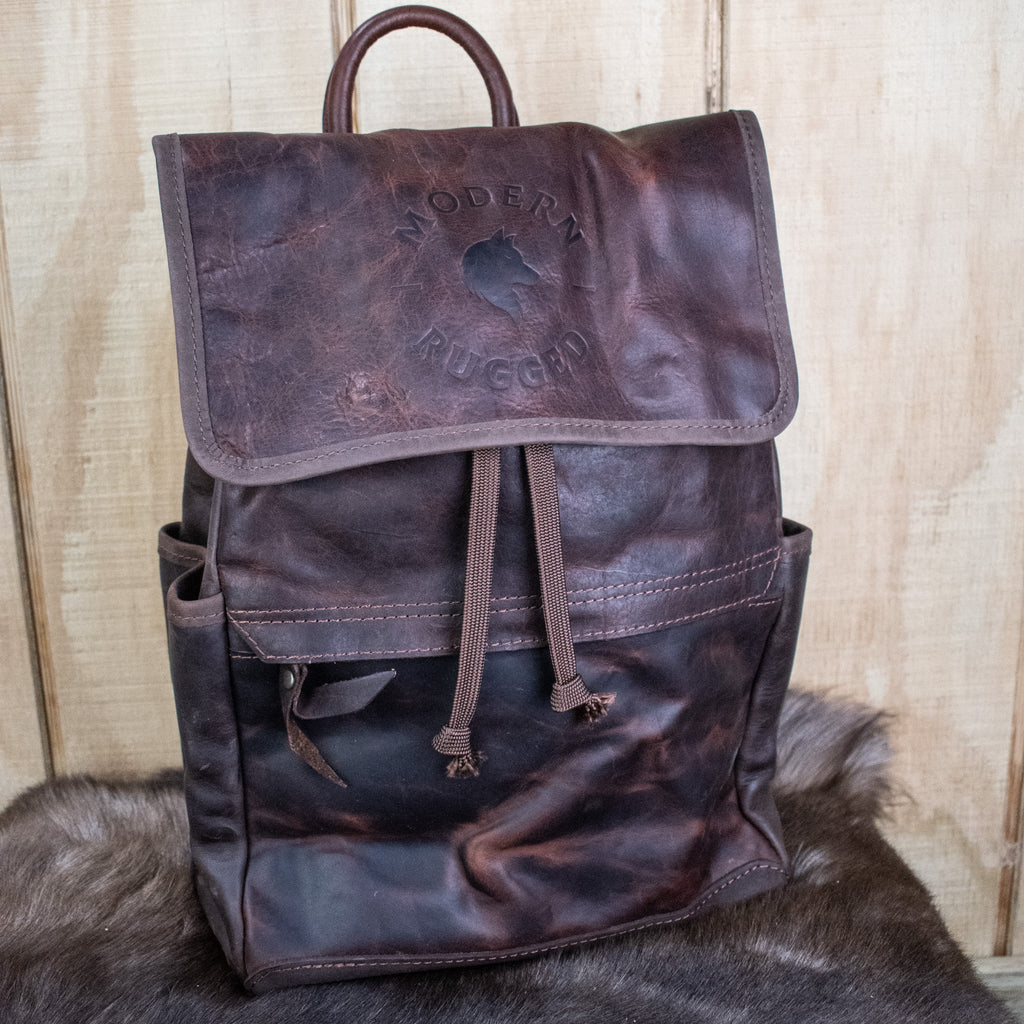 Leather Hide Backpack - Mahogany and Brown with a rustic finish featuring the Modern Rugged logo with wolf head and a lifetime warranty on stitching and hardware