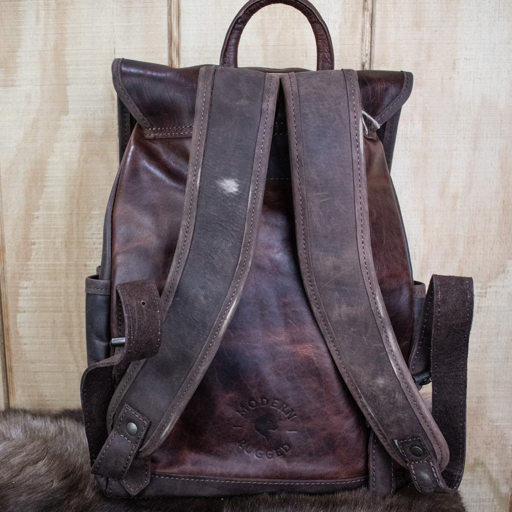 Leather Hide Backpack - Mahogany and Brown with a rustic finish featuring the Modern Rugged logo with wolf head and a lifetime warranty on stitching and hardware