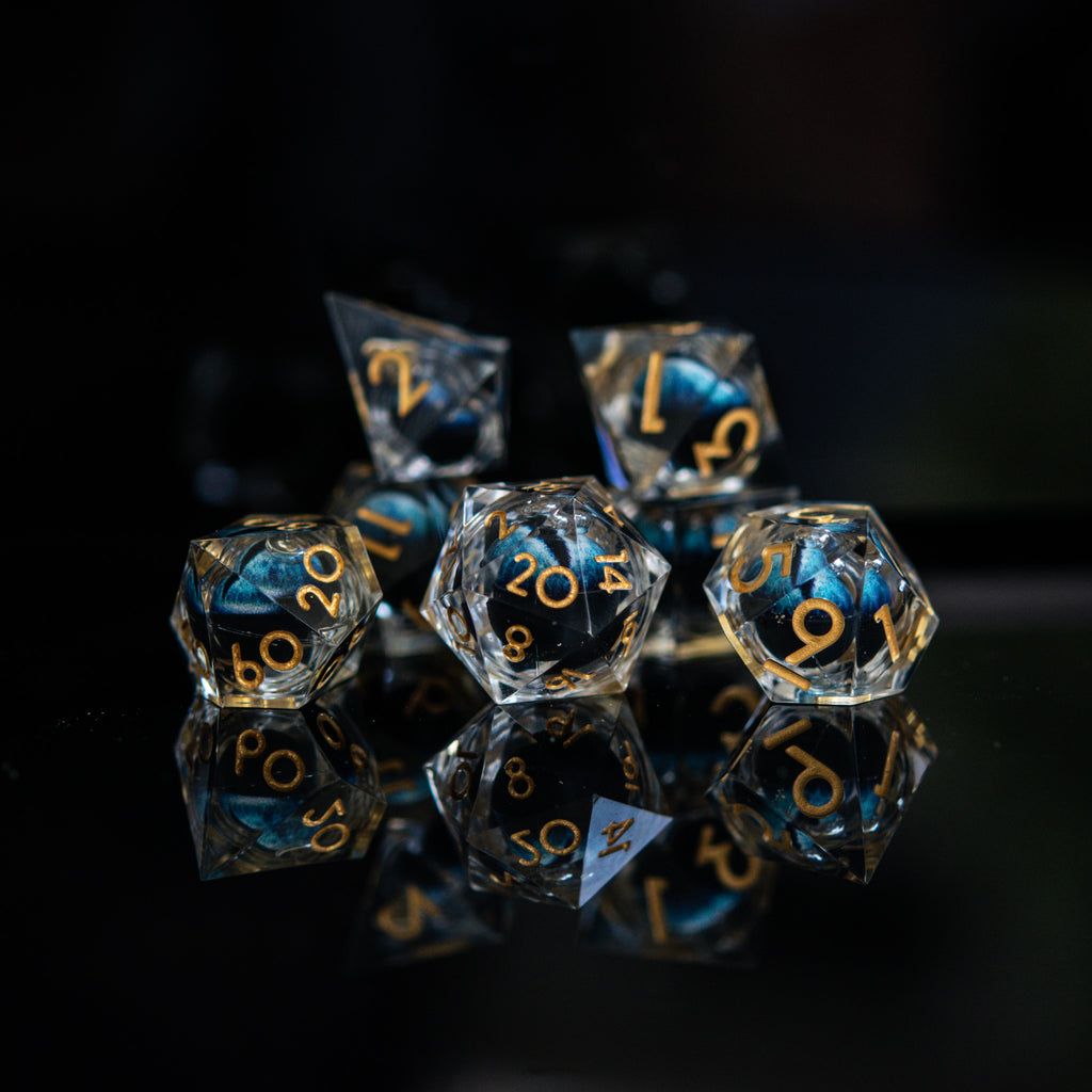 Close-up of polyhedral dice with blue and gold numbers on a reflective surface.