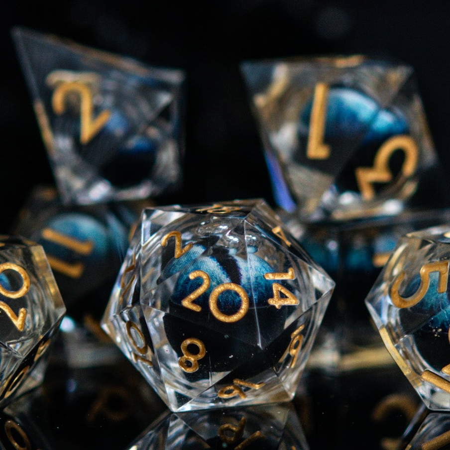 Close-up of polyhedral dice with blue and gold numbers on a reflective surface.