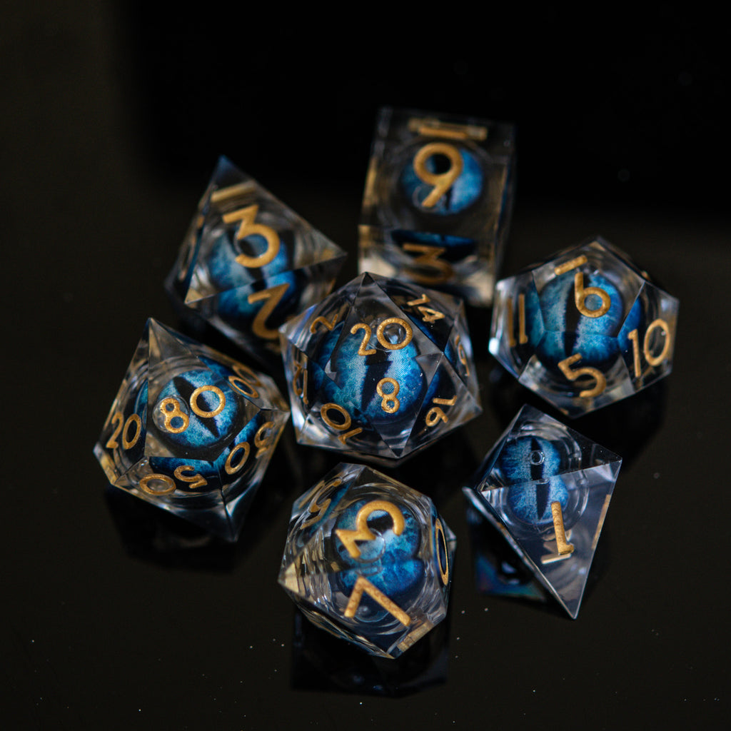 A set of blue resin dice with engraved numbers, featuring a unique eye design in the center, displayed on a black background.