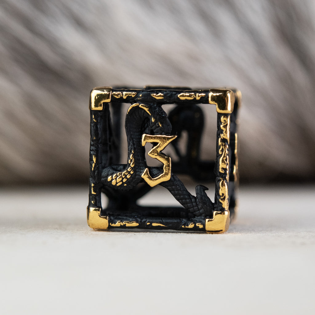A set of matte black and gold hollow metal dice with embossed numbers, including various shapes such as a d4, d6, d8, d10, d12, and d20, displayed on a white surface.