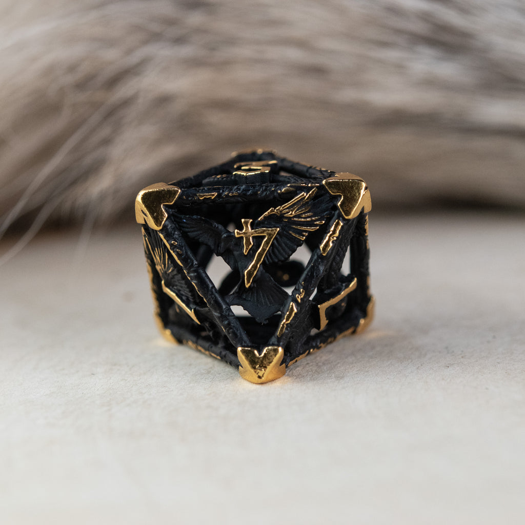 A set of matte black and gold hollow metal dice with embossed numbers, including various shapes such as a d4, d6, d8, d10, d12, and d20, displayed on a white surface.