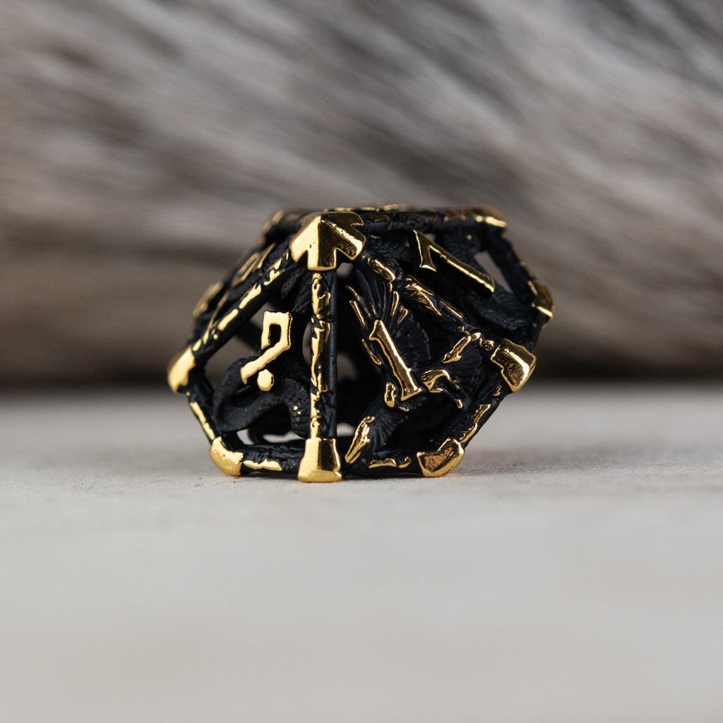 A set of matte black and gold hollow metal dice with embossed numbers, including various shapes such as a d4, d6, d8, d10, d12, and d20, displayed on a white surface.