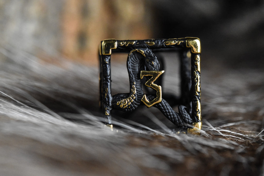 A set of matte black and gold hollow metal dice with embossed numbers, including various shapes such as a d4, d6, d8, d10, d12, and d20, displayed on a white surface.