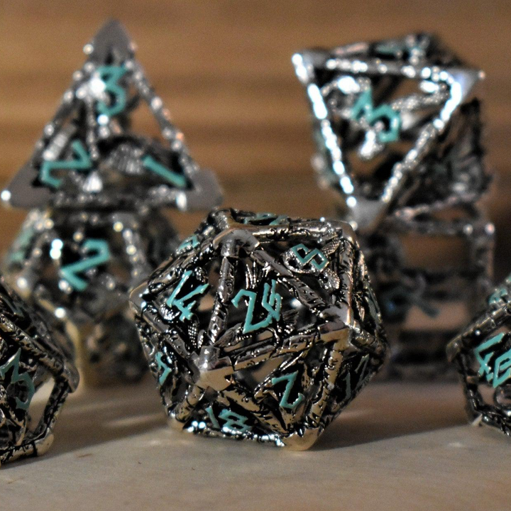 A set of silver and blue hollow metal dice with embossed numbers, displayed on a wooden surface.