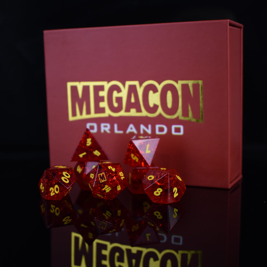 A set of red glass dice with engraved numbers, displayed in front of a Megacon Orlando backdrop.