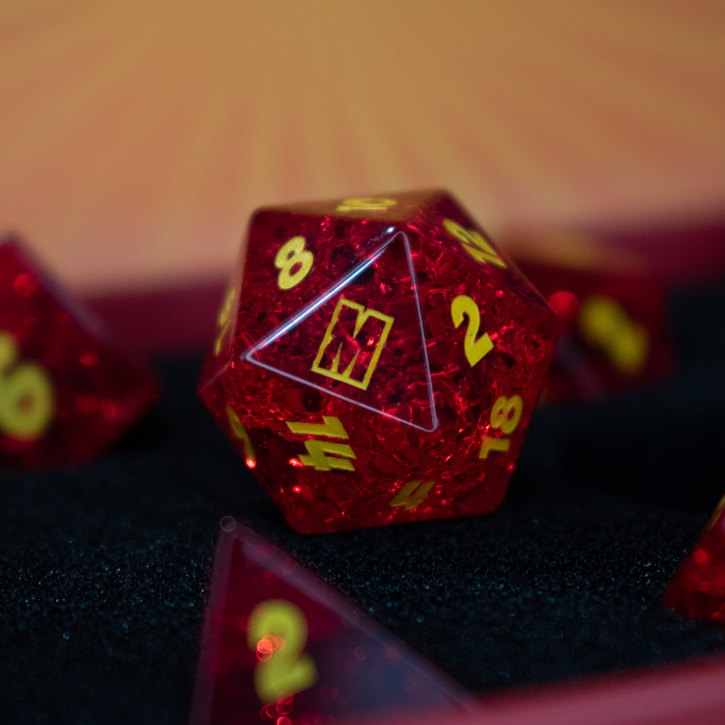 A set of red glass dice with engraved numbers, displayed in front of a Megacon Orlando backdrop.