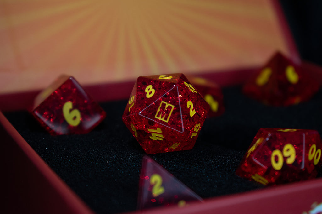 A set of red glass dice with engraved numbers, displayed in front of a Megacon Orlando backdrop.
