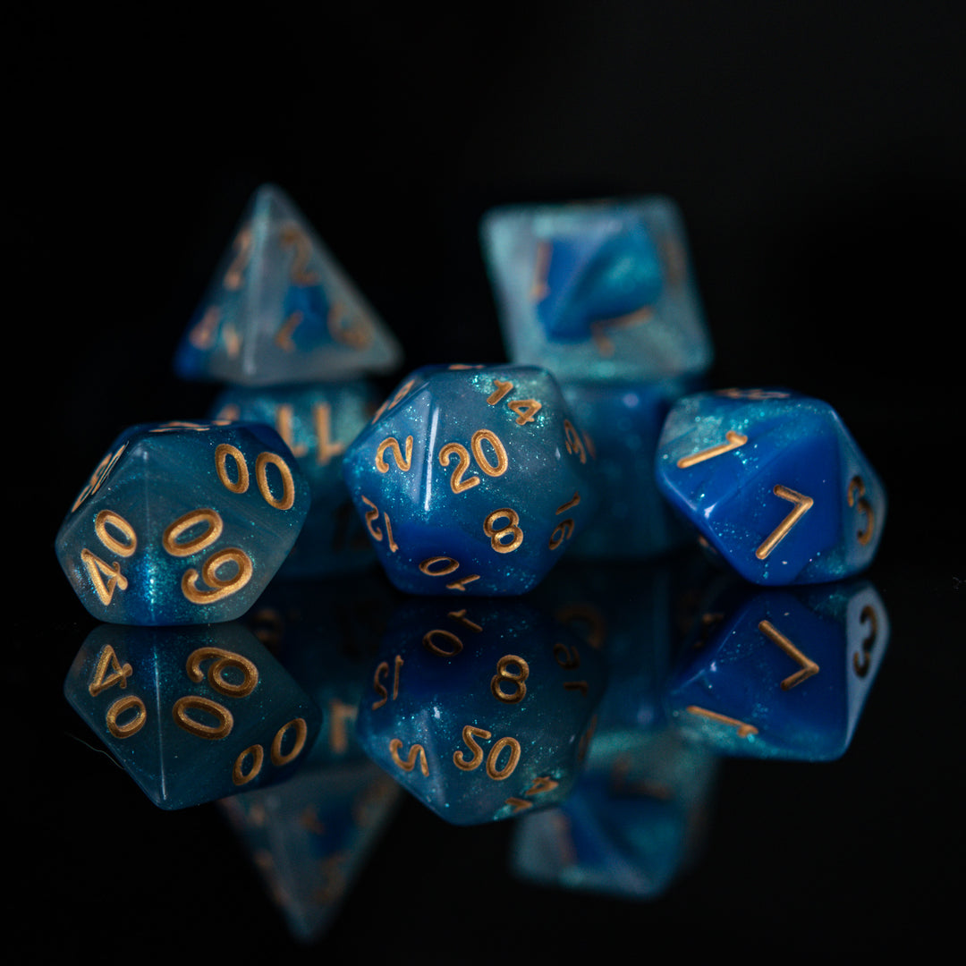 A set of blue acrylic dnd dice with engraved gold numbers, displayed on a reflective surface for dungeons and dragons 