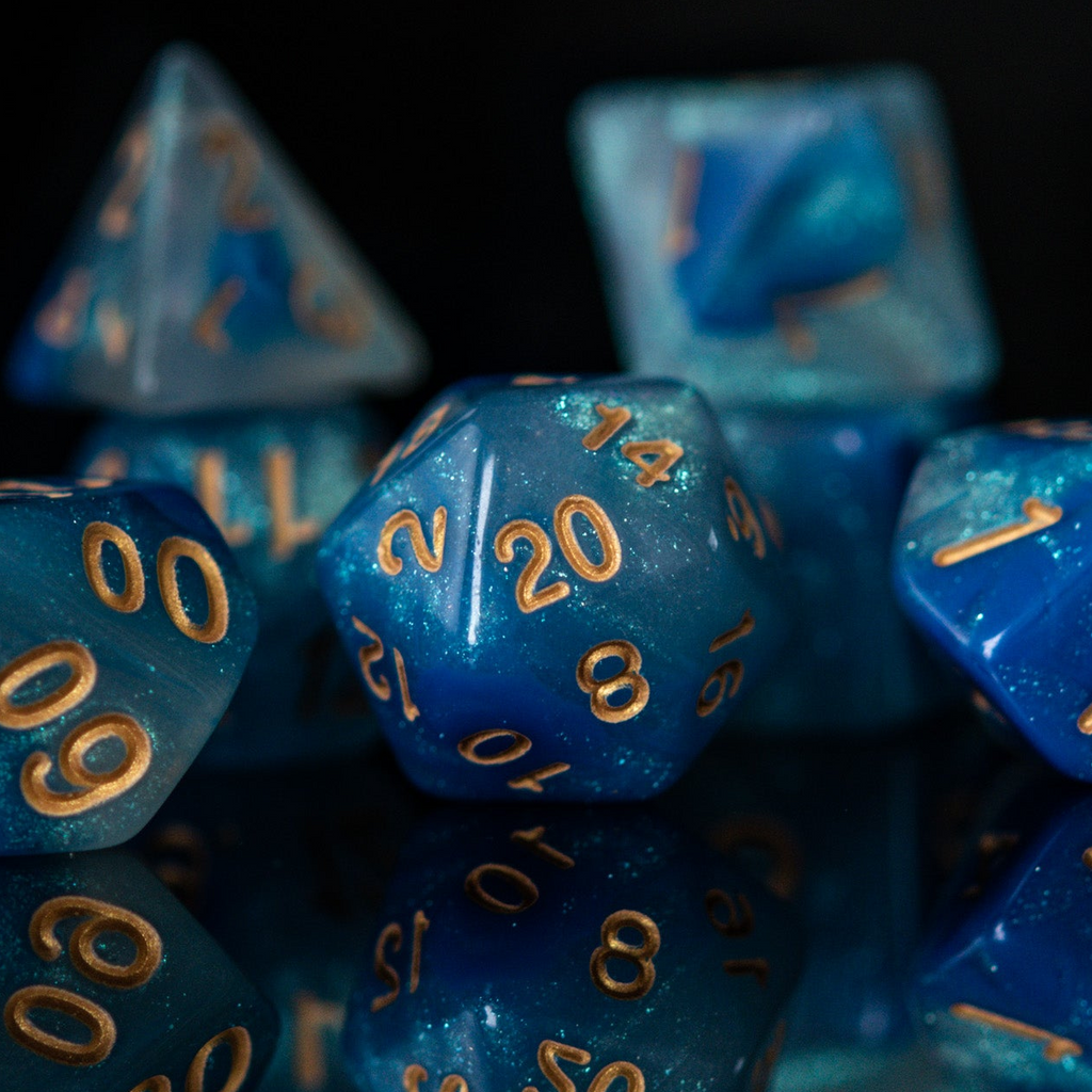 Blue polyhedral dice with gold numbers on a reflective surface