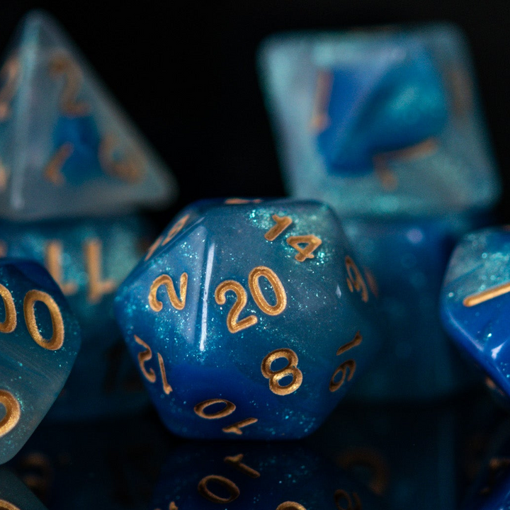 A set of blue acrylic dnd dice with engraved gold numbers, displayed on a reflective surface for dungeons and dragons 