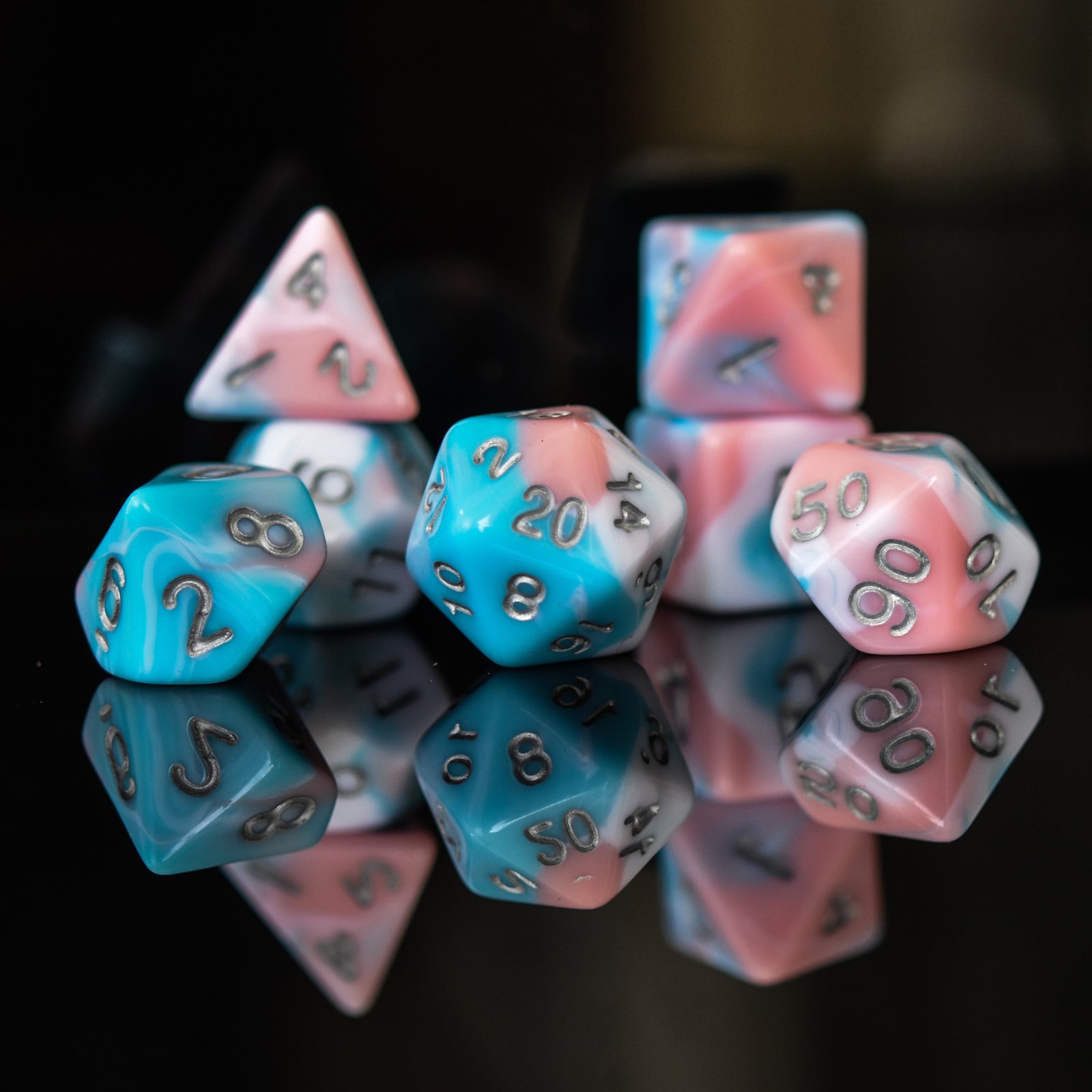 A set of baby blue, pink and white acrylic dnd dice with silver numbers for playing tabletop games