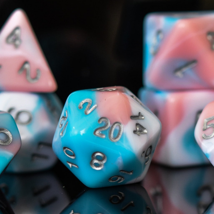 A set of baby blue, pink and white acrylic dnd dice with silver numbers for playing tabletop games